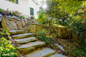 stone steps leading up to a path between retaining walls in a residential yard